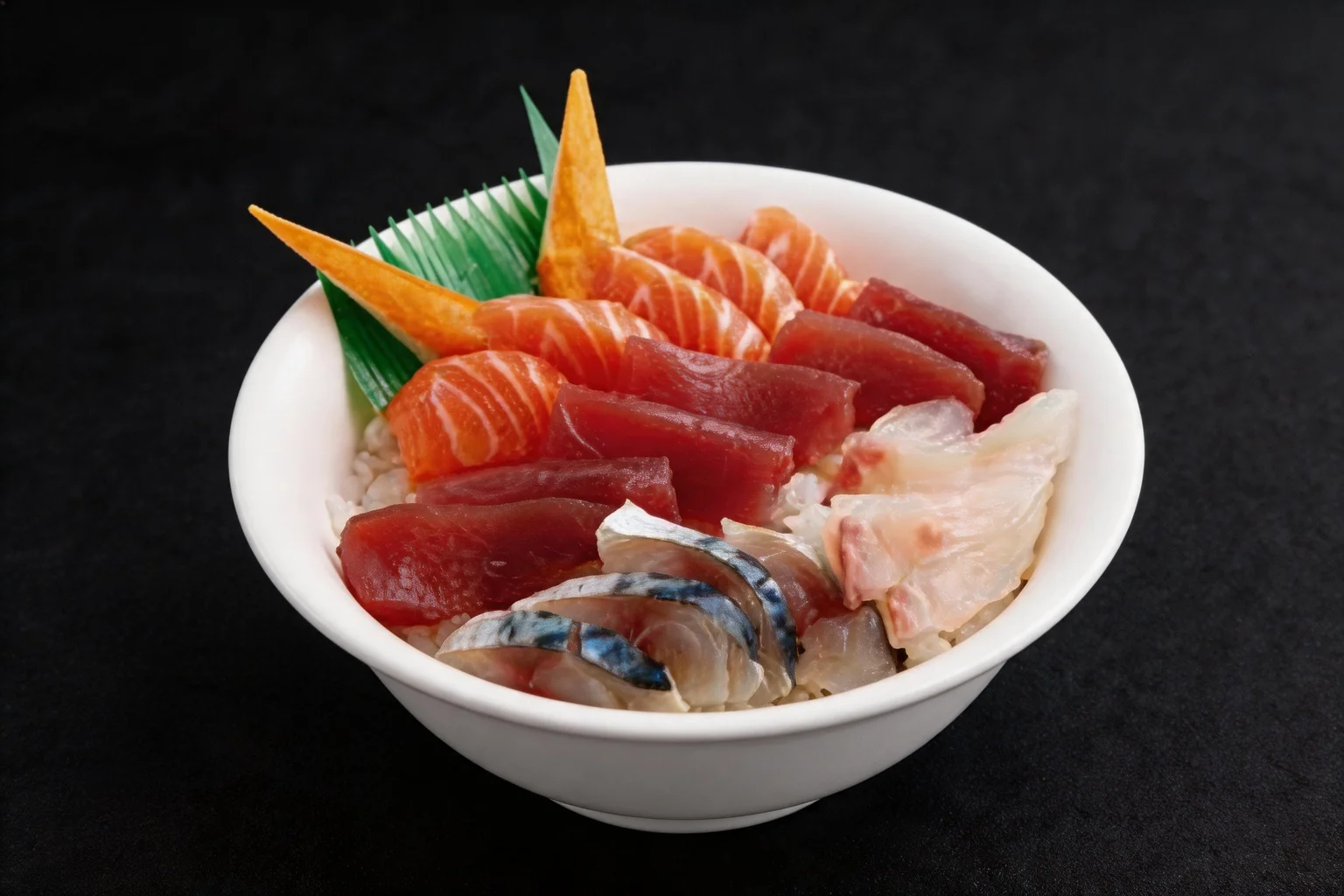 White bowl of chirashi: vinegared rice topped with slices of raw salmon and tuna, garnished with a leaf and a slice of carrot.