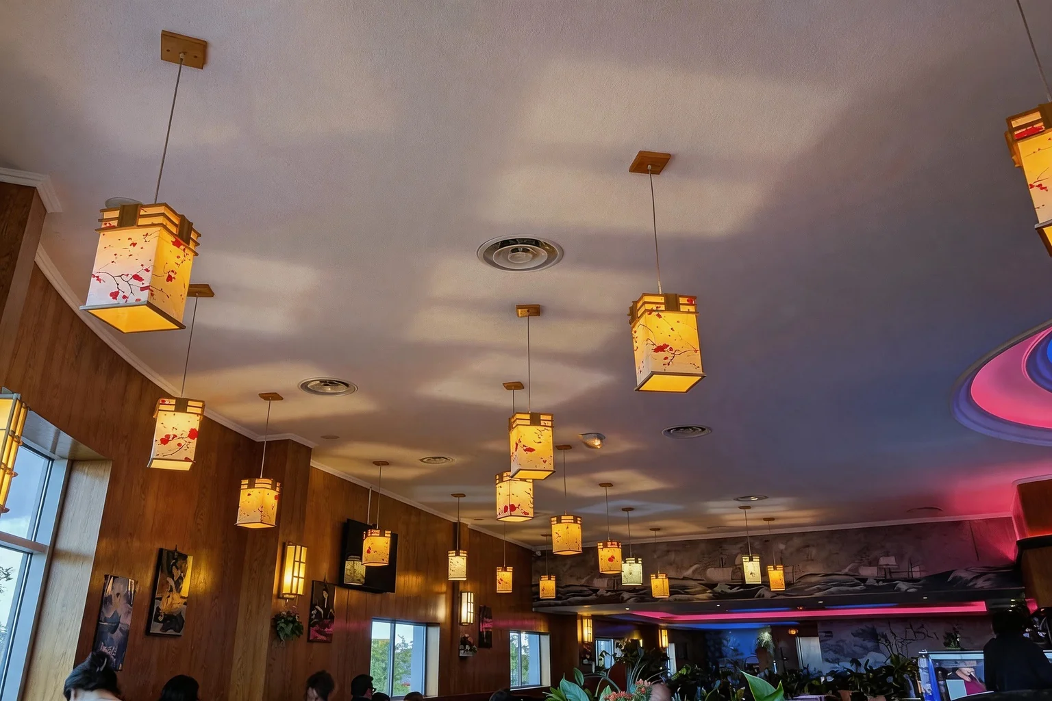 Japanese lantern pendant lights on the restaurant ceiling, warm light, windows in the background.