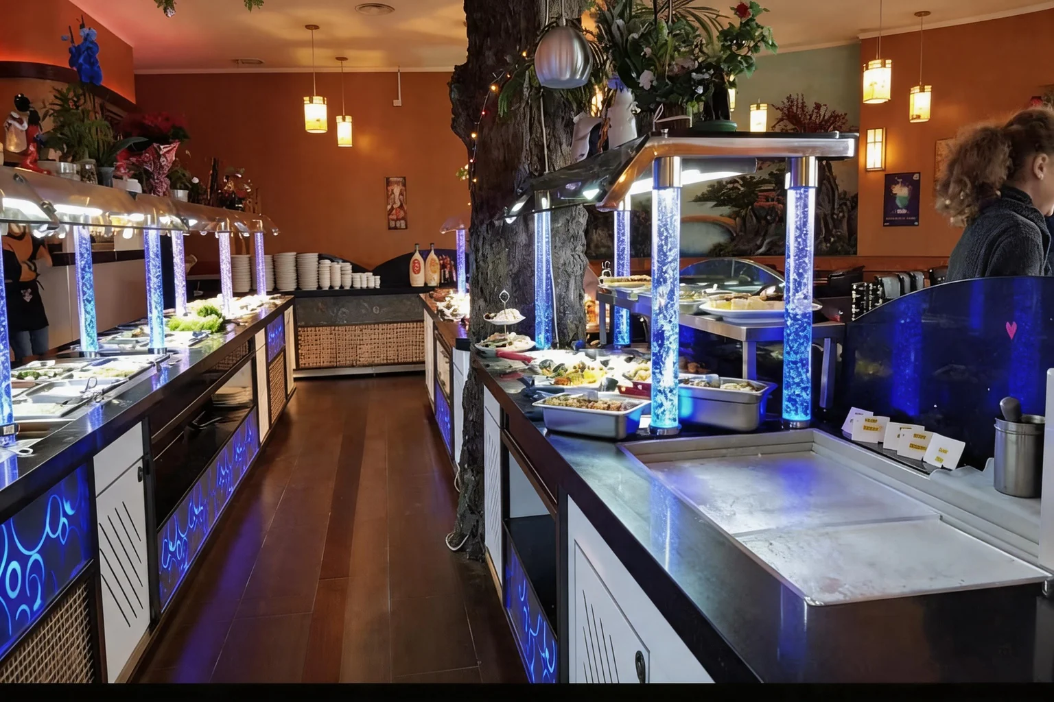 Buffet counter with blue-lit stainless trays and tree decoration.